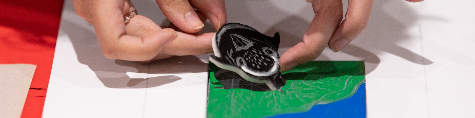 Hands placing a bird linocut block