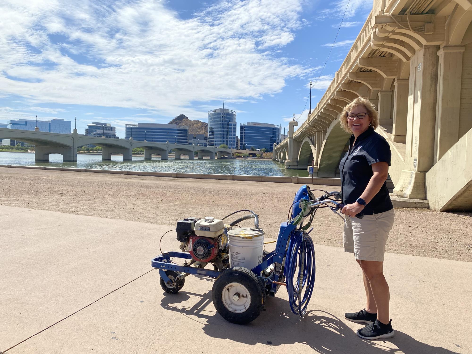 Councilmember Jennifer Adams helps to add bi-directional striping on the pedestrian/bike path at Tempe Town Lake