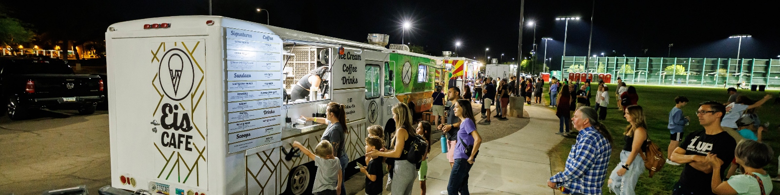 Three food trucks with lines of people waiting