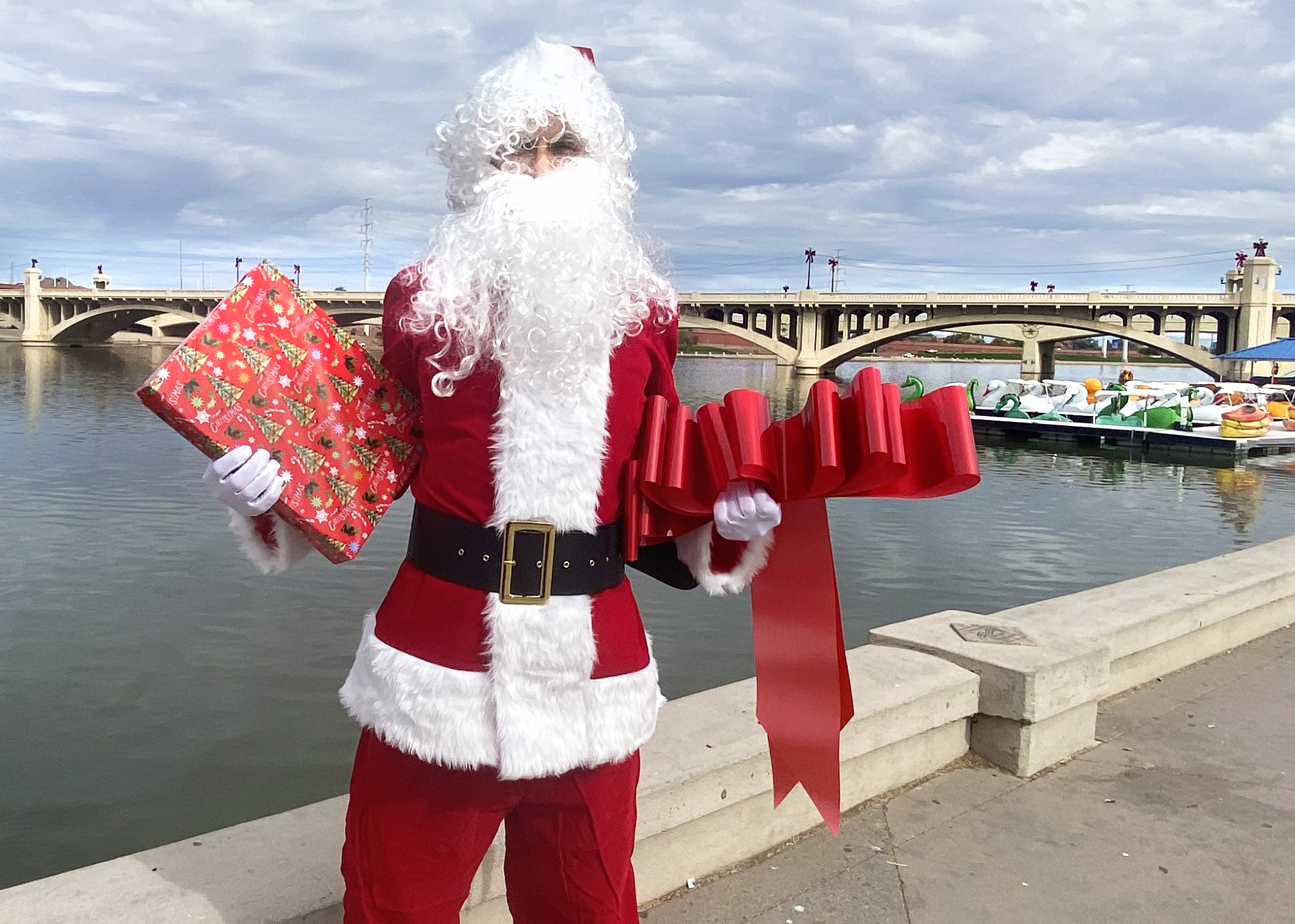 Santa posing with presents in front of Tempe Town Lake