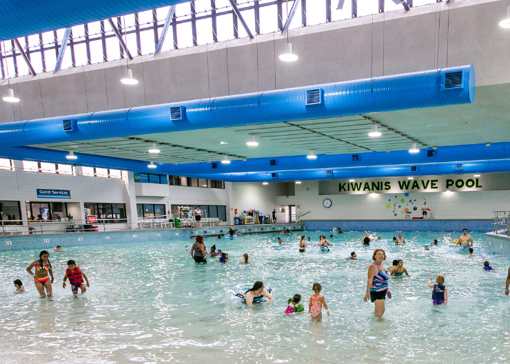 Wide photo of groups of people swim in the calm waters at Kiwanis Pool