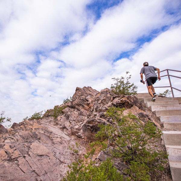 A hiker ascends Hayden Butte on a partly cloudy day