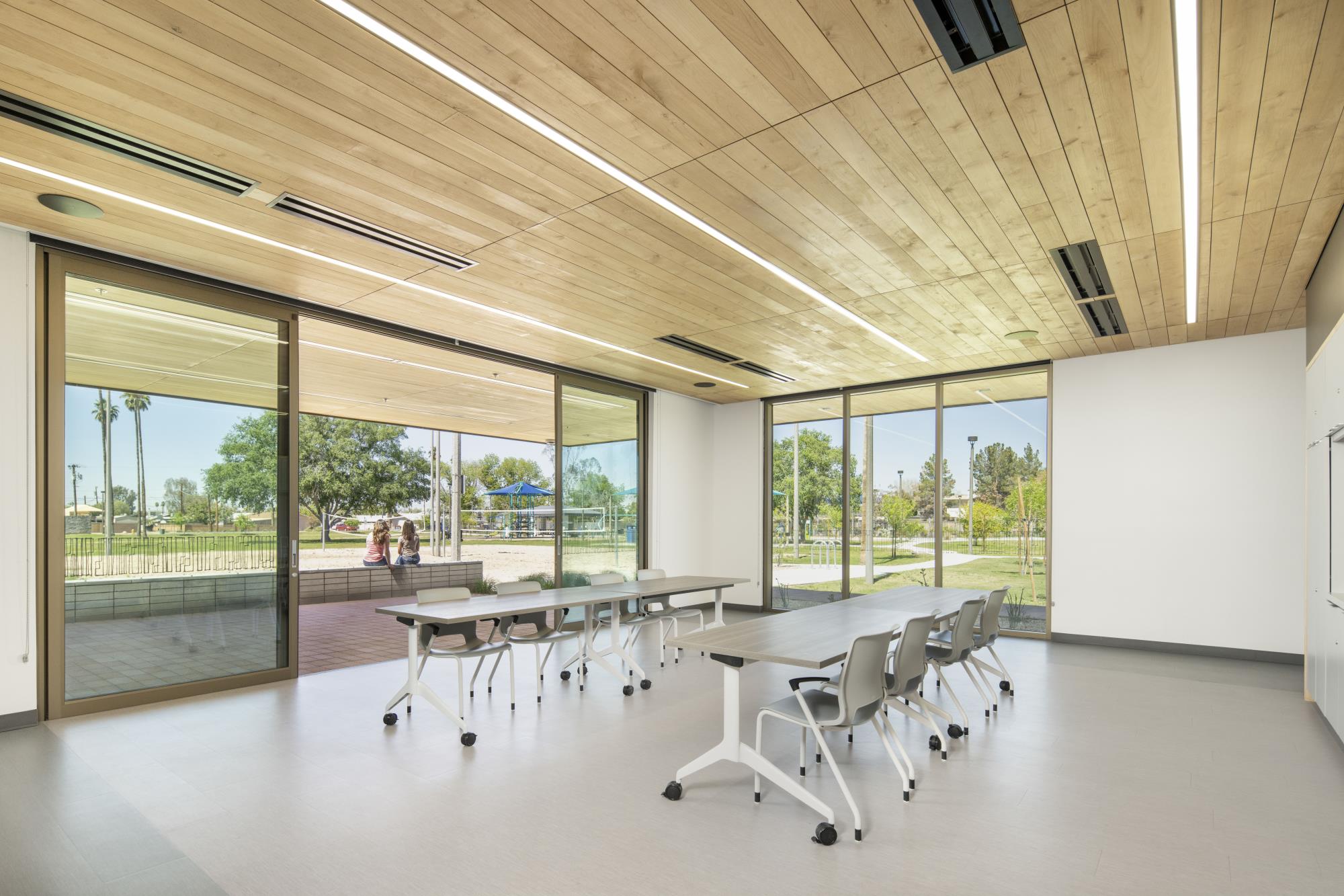 Image of a brightly lit classroom with tables and large windows.